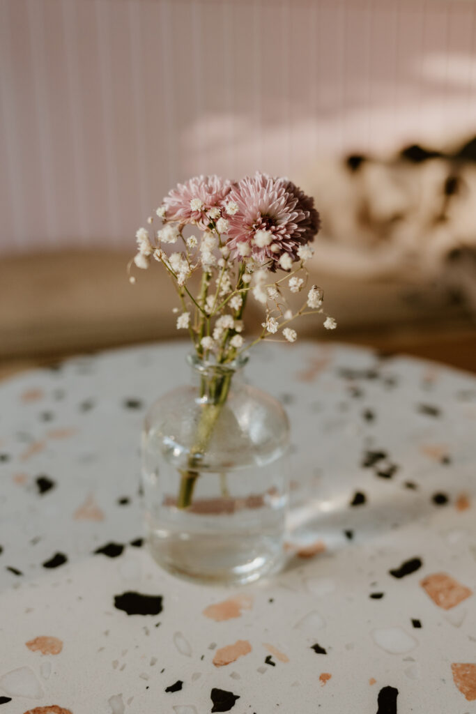A delicate vase of pink flowers rests on a speckled cafe table, bringing a touch of elegance to Elixxr Cafe in Beacon.