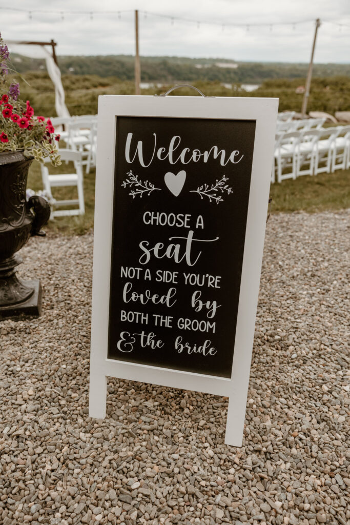 Charming wedding ceremony sign with a heartfelt message welcoming guests to choose a seat, not a side.
