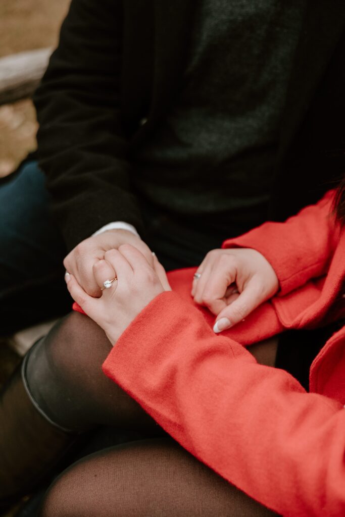 Close-up of a couple holding hands, highlighting the engagement ring during their winter engagement session at Mohonk Mountain House.