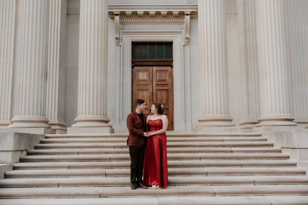 Engaged couple holding hands on the grand steps of Vanderbilt Mansion in Hyde Park, NY during their engagement session.