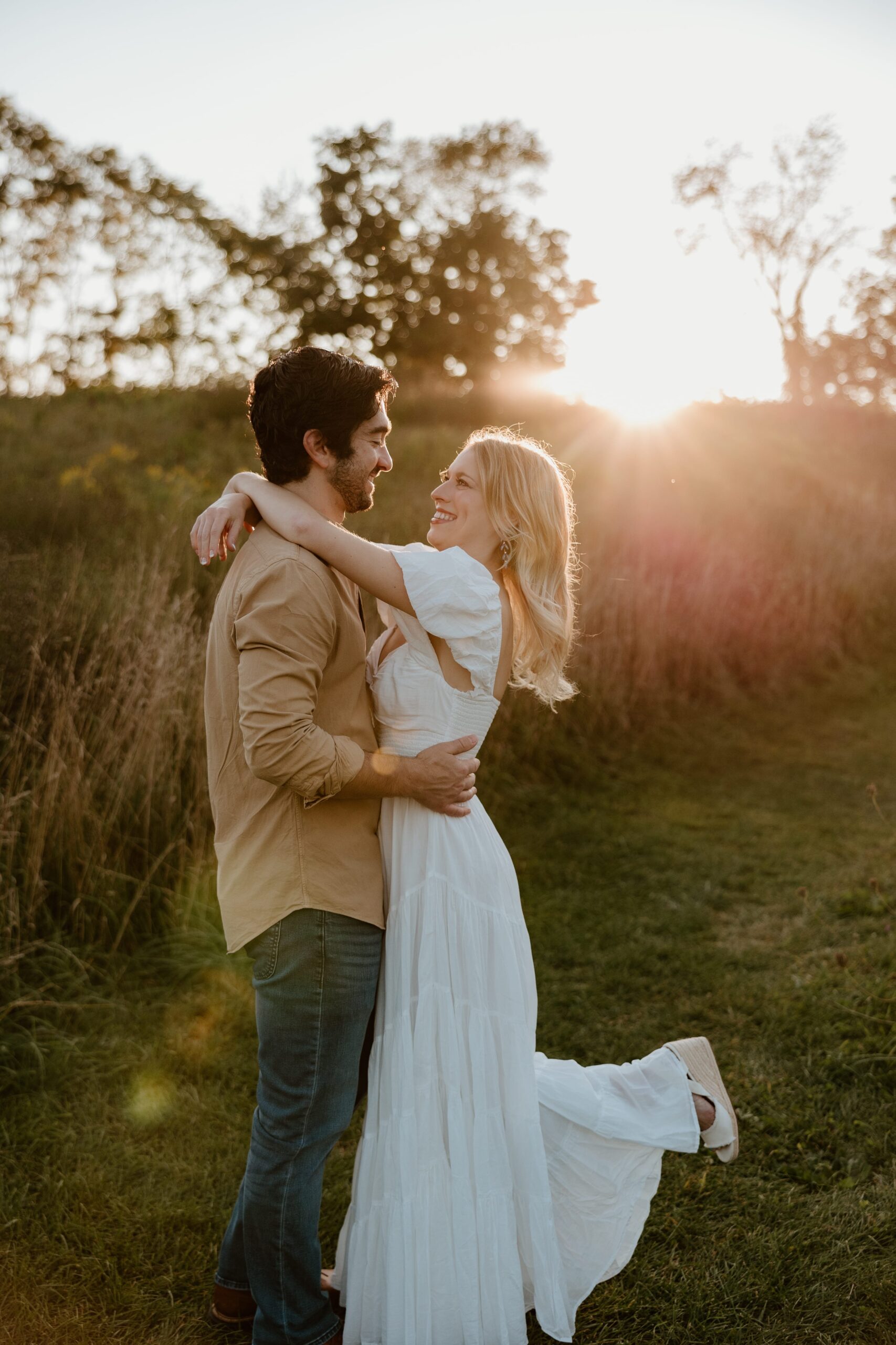 Couple embracing during a sunset engagement session in a scenic Hudson Valley field.