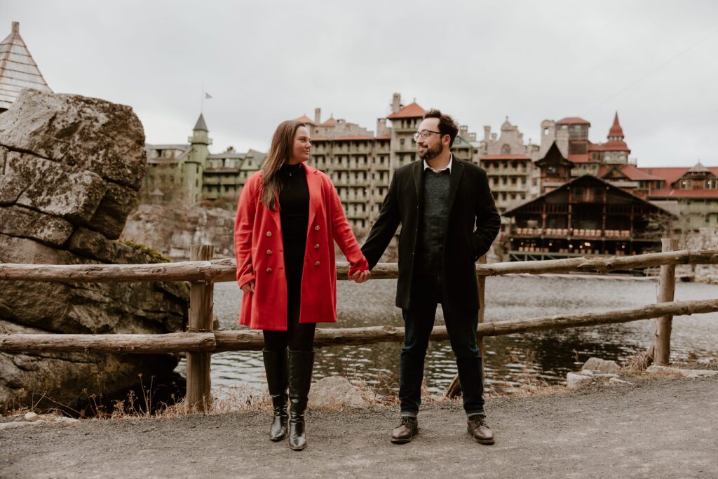 Couple holding hands in front of the iconic Mohonk Mountain House during their engagement session in the Hudson Valley.