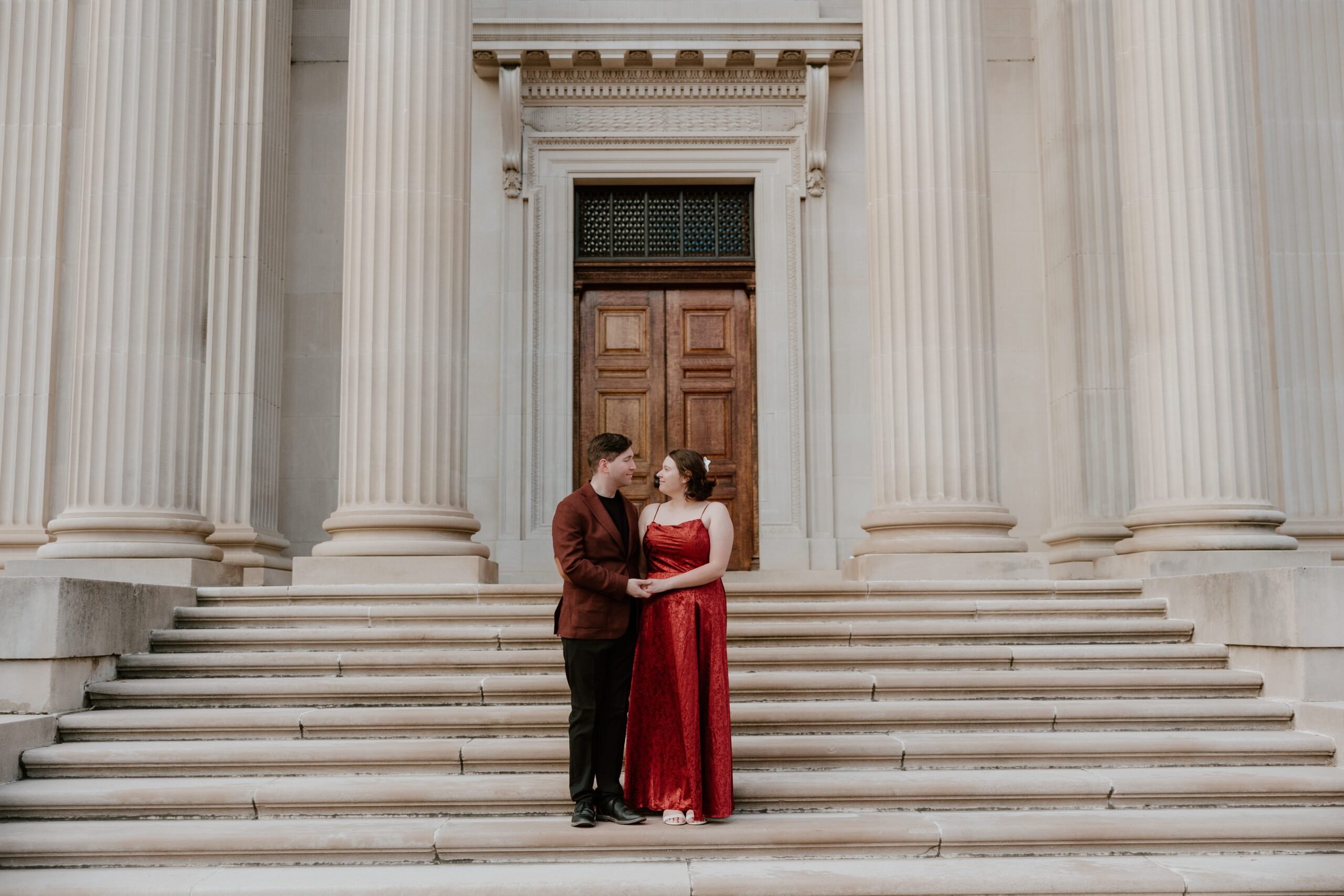 Engaged couple posing on the grand steps of Vanderbilt Mansion in Hyde Park, NY during a romantic engagement session.