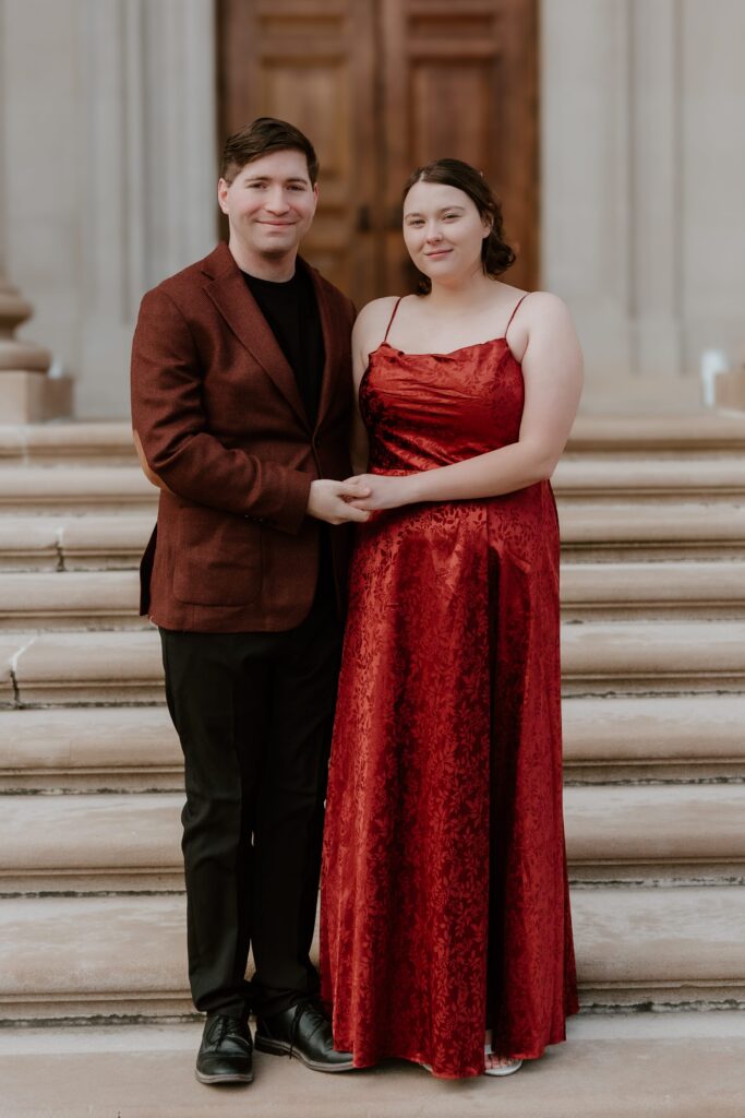 A couple holding hands on the elegant steps of Vanderbilt Mansion, captured during their romantic engagement session in the Hudson Valley.