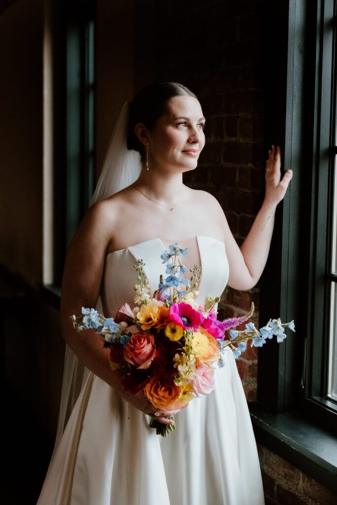 Bride holding colorful bouquet by window light