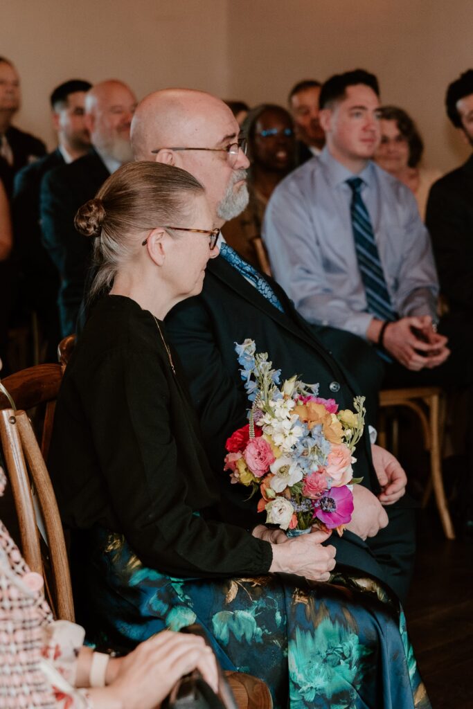 Wedding guests watching the ceremony at Drowned Lands Brewery in Warwick NY, holding a colorful bouquet