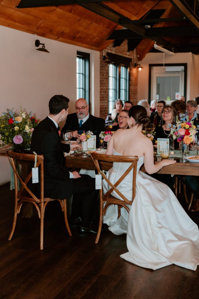 Bride and groom seated with guests during intimate wedding dinner at Drowned Lands Brewery in Warwick NY