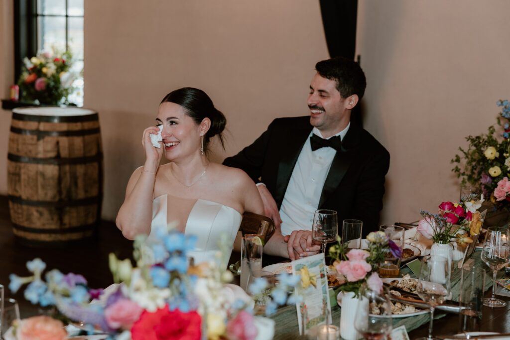 Bride laughing and tearing up during a heartfelt reception moment at Drowned Lands Brewery wedding in Warwick NY