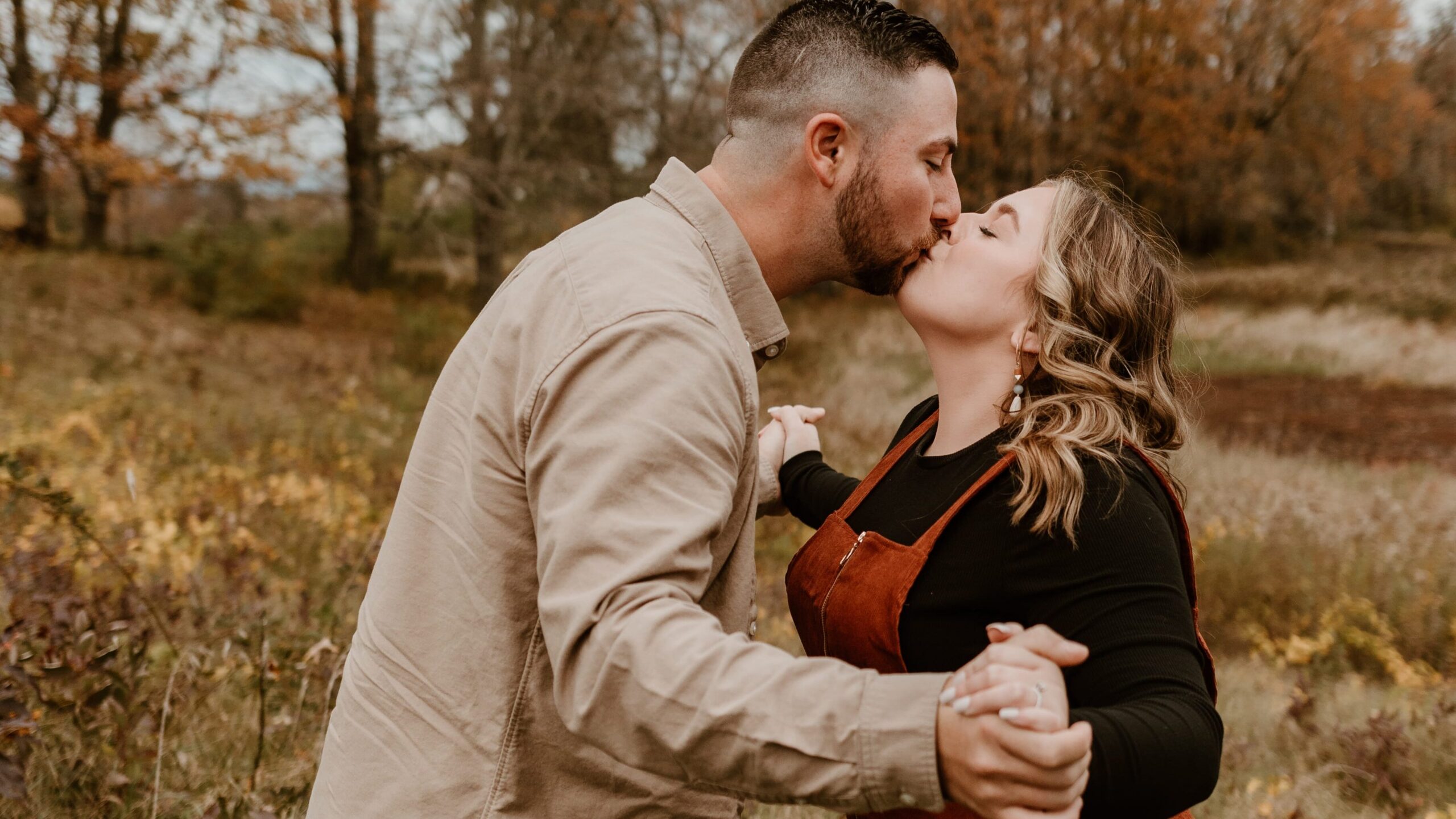 Couple kissing in a field during a fall photo session at Burger Hill in Rhinebeck, NY.