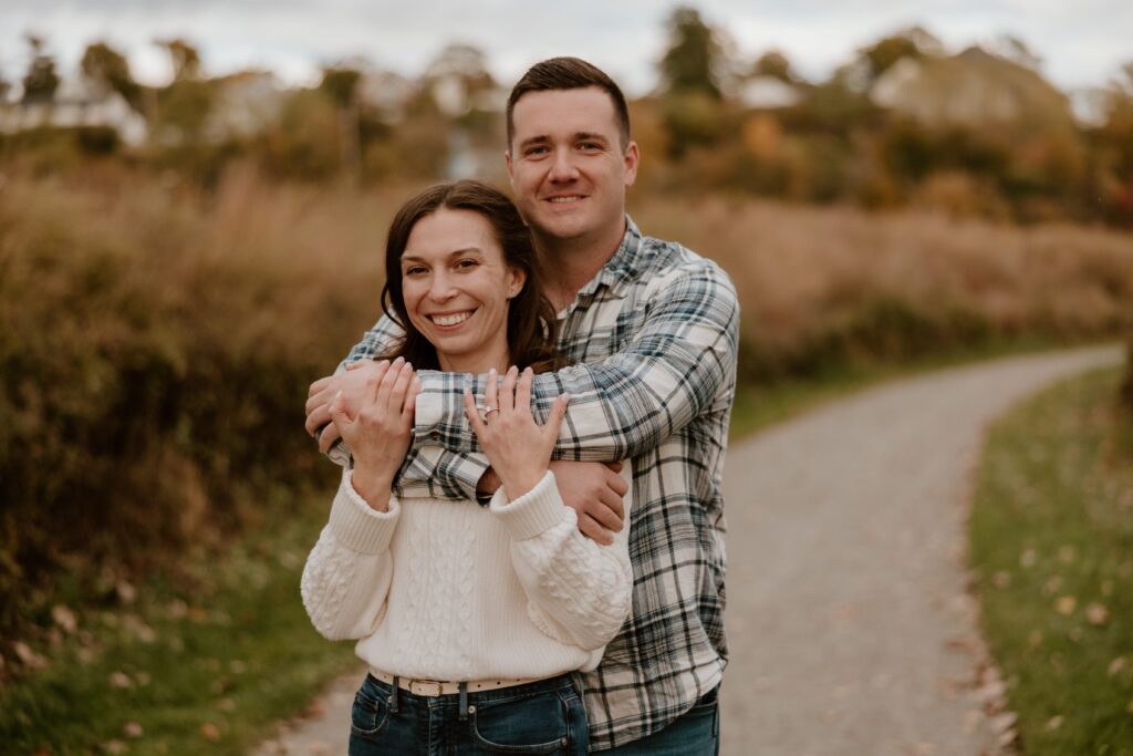Engaged couple embracing on a walking path at Long Dock Park in Beacon, NY during a fall photo session.