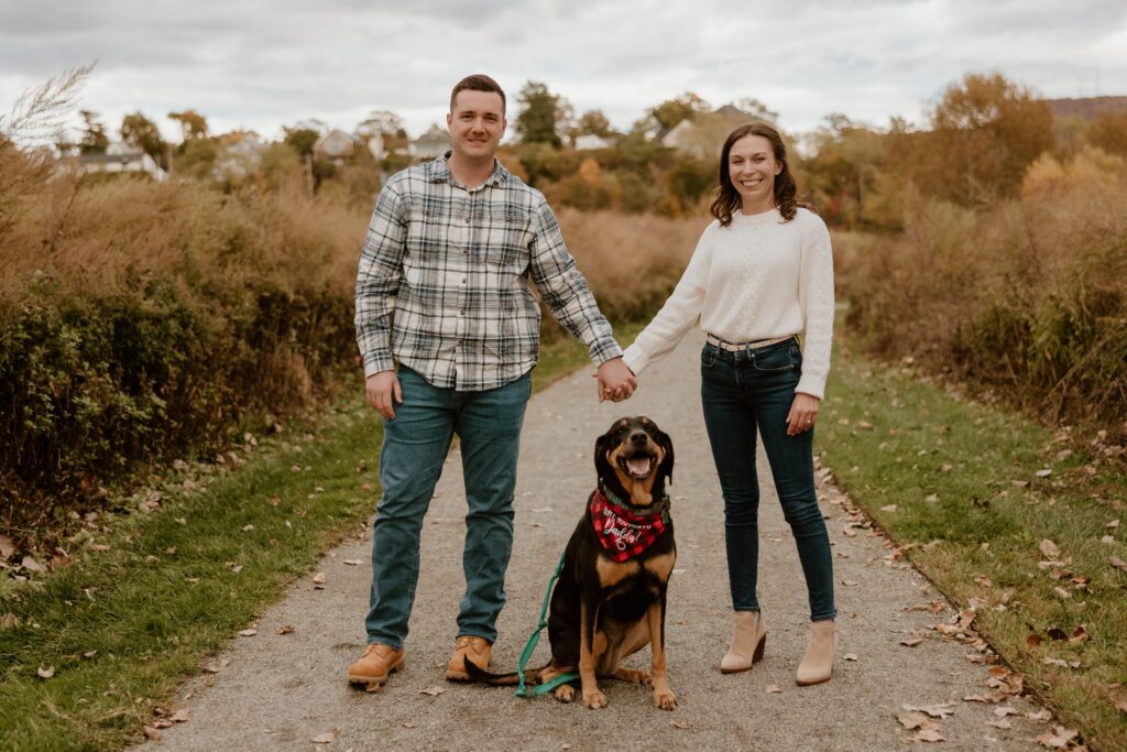 Couple posing with their dog at Long Dock Park in Beacon, NY during a fall photo session in the Hudson Valley.
